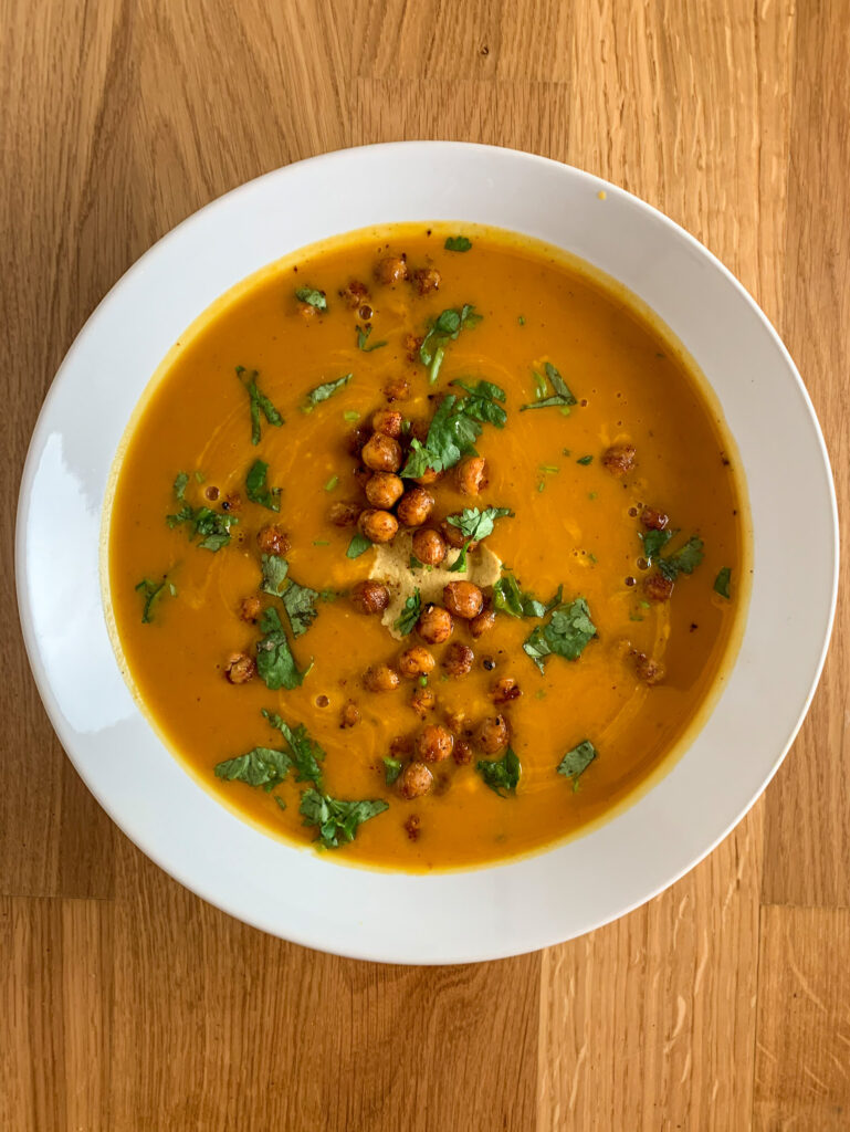 Gorgeous Ginger Pumpkin Soup with Crispy Curried Chickpeas topped with a dollop of tahini and chopped cilantro 