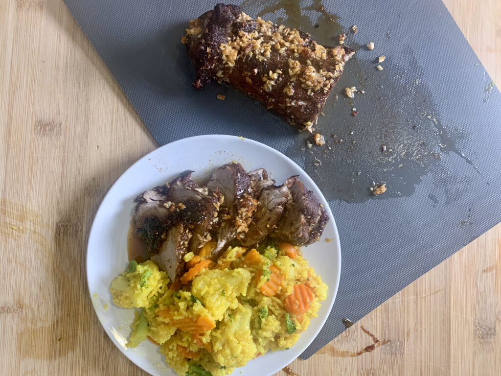 Island Pork with Tumeric Rice on a cutting board and plated next to it. 